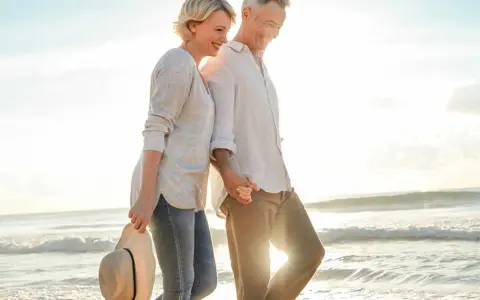 Un couple profite d'un rendez-vous amoureux sur la plage, main dans la main, au coucher du soleil.