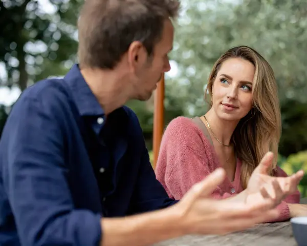 Un homme parle à une femme, son regard captivé par elle. Elle semble écouter attentivement, son expression suggérant le **hero instinct**.