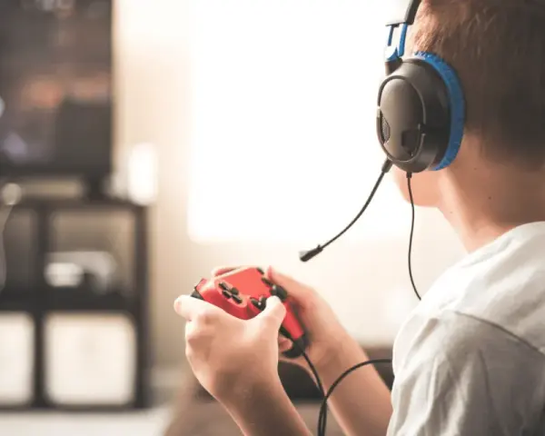 Un jeune homme, casque sur les oreilles, manette rouge en main, plongé dans ses jeux vidéos. Il semble que mon mec préfère ses jeux vidéos à moi.