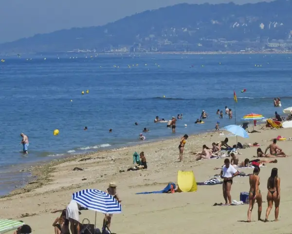 Plage bondée, baigneurs dans l'eau bleue. Combien de temps avant d'aller chez lui ? La journée s'étire.
