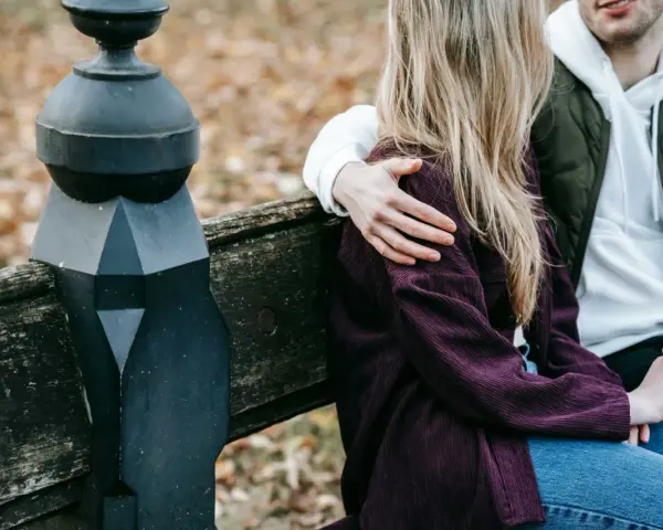 Un homme enlace tendrement une femme assise à ses côtés sur un banc. Un geste qui dit "comment dire je t'aime sans le dire".