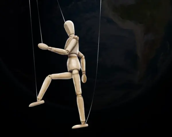 Marionnette de bois suspendue par des fils, se faisant désirer devant la Terre.
