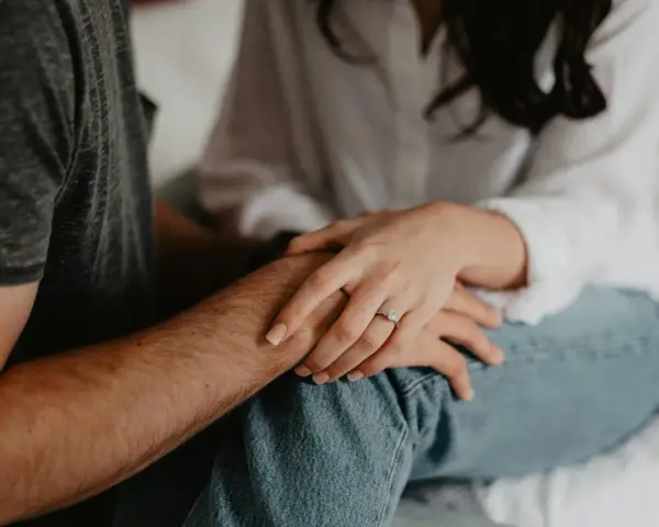 Mains jointes, une bague orne le doigt de la femme, symbole de l'effet boomerang en amour : ce qui est donné revient toujours.