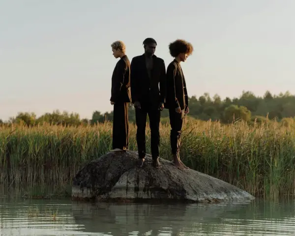 Trois personnes en noir, sur un rocher au milieu de l'eau, symbolisant la non monogamie éthique et la liberté de choix.
