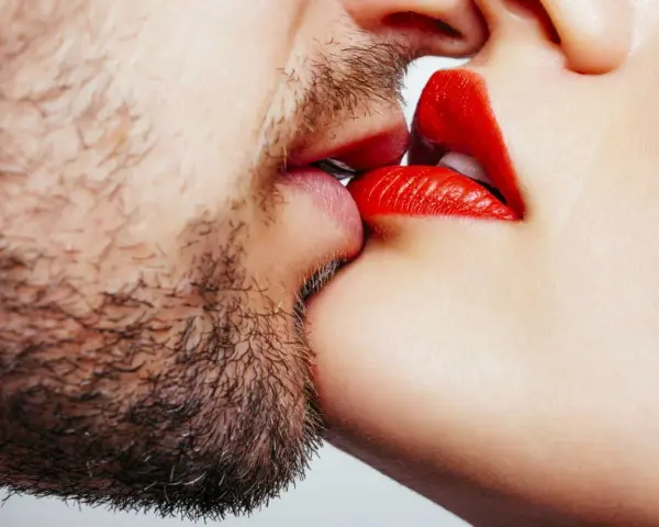 Un homme barbu et une femme aux lèvres rouges apprennent comment embrasser.