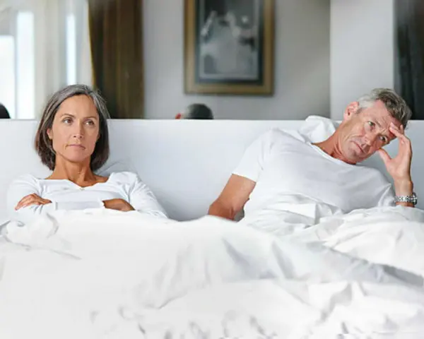 Couple au lit, elle est fâchée, lui semble préoccupé par une perte libido homme 60 ans.
