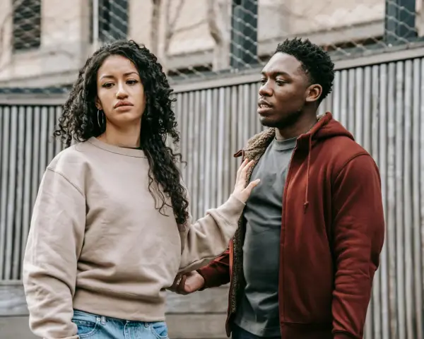 Un homme et une femme se regardent, l'air préoccupé. Sa main sur son bras suggère une tentative de connexion, mais son expression montre qu'il ne veut plus donner de nouvelles, quel effet sur les hommes.