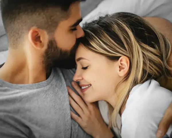 Un homme embrasse le front d'une femme endormie, un moment de tendresse calin amoureux.