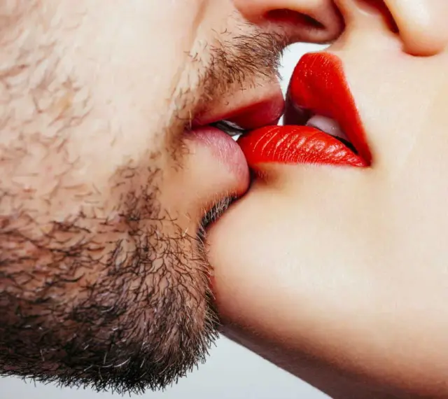 Un homme barbu et une femme aux lèvres rouges apprennent comment embrasser.