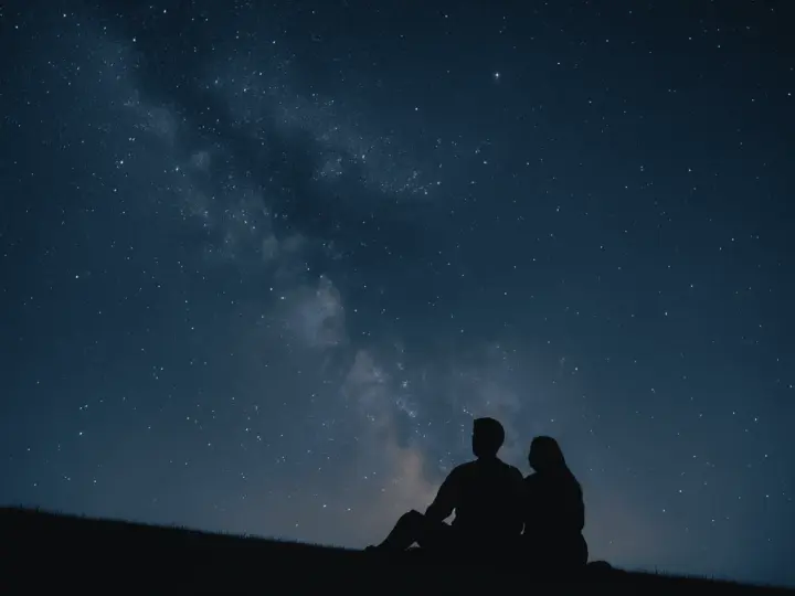 Un couple en silhouette admire la Voie lactée. Une idée de rendez-vous romantique parfait sous les étoiles.
