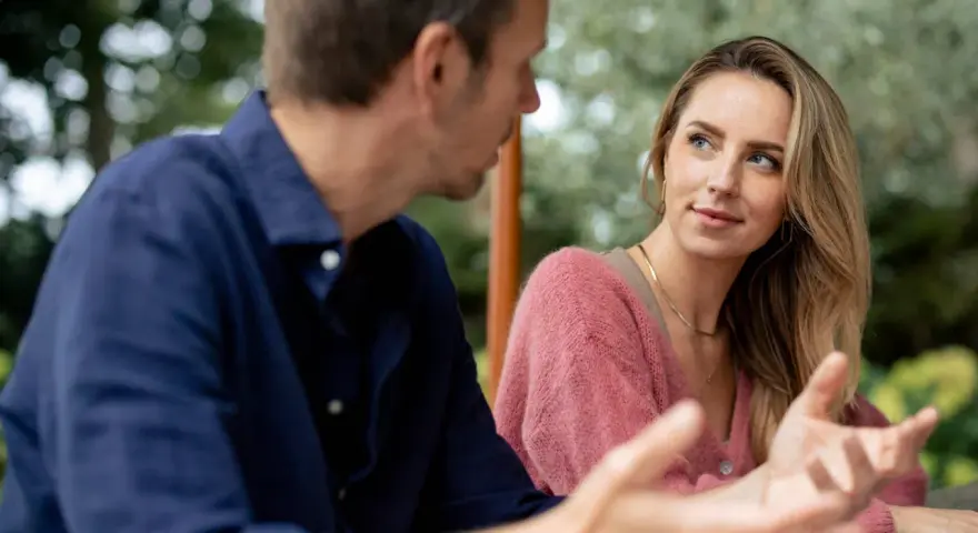 Un homme parle à une femme, son regard captivé par elle. Elle semble écouter attentivement, son expression suggérant le **hero instinct**.
