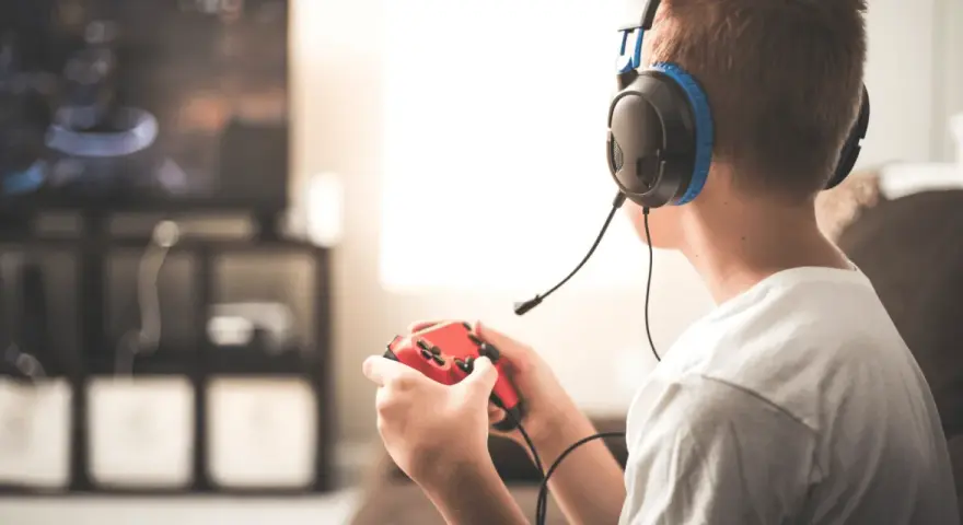 Un jeune homme, casque sur les oreilles, manette rouge en main, plongé dans ses jeux vidéos. Il semble que mon mec préfère ses jeux vidéos à moi.