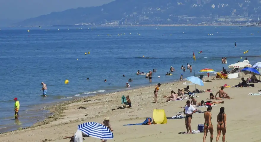 Plage bondée, baigneurs dans l'eau bleue. Combien de temps avant d'aller chez lui ? La journée s'étire.