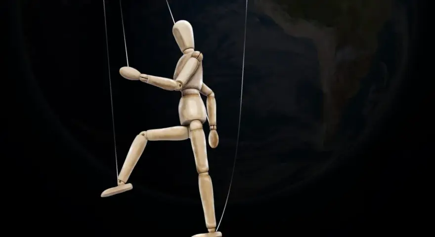 Marionnette de bois suspendue par des fils, se faisant désirer devant la Terre.