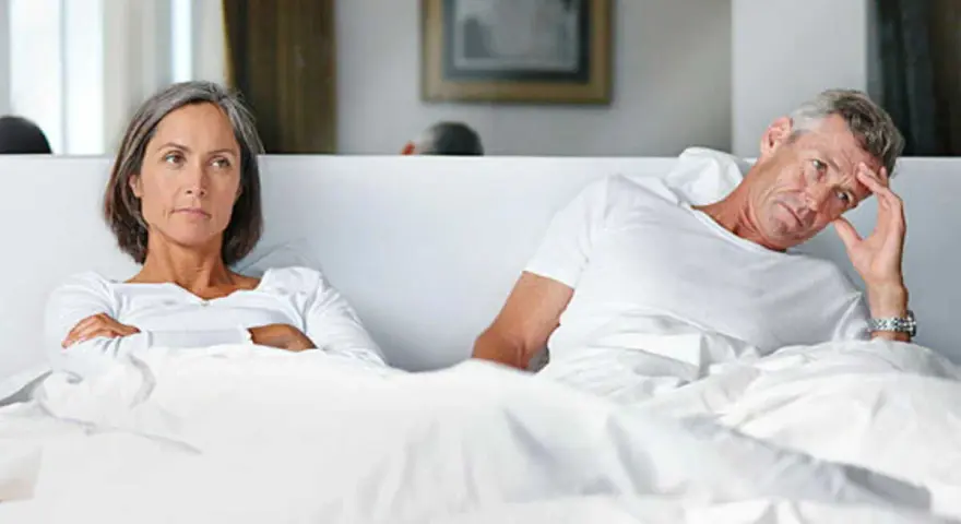 Couple au lit, elle est fâchée, lui semble préoccupé par une perte libido homme 60 ans.
