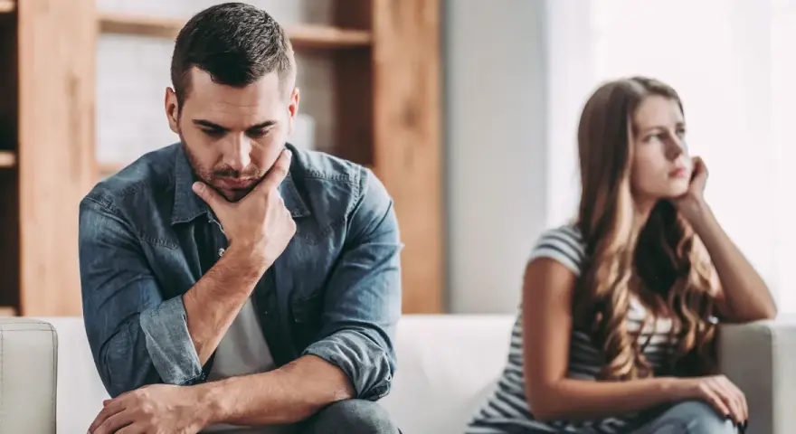 Un homme pensif, peut-être un homme qui trouve toujours des excuses, est assis à côté d'une femme qui regarde au loin, le couple semble distant.
