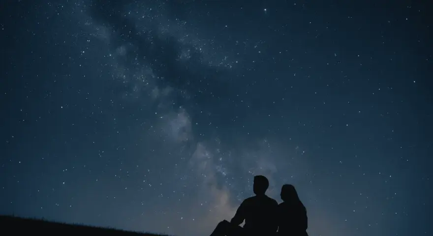 Un couple en silhouette admire la Voie lactée. Une idée de rendez-vous romantique parfait sous les étoiles.