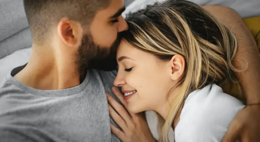 Un homme embrasse le front d'une femme endormie, un moment de tendresse calin amoureux.