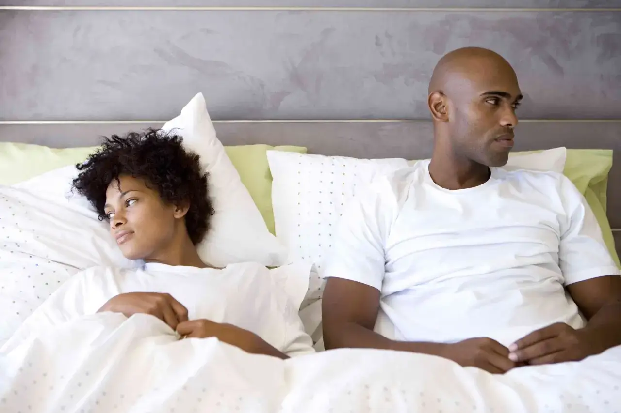 Un couple dans un lit, visiblement distant. L'homme, chauve, regarde ailleurs, sugg&eacute;rant une baisse de libido homme.