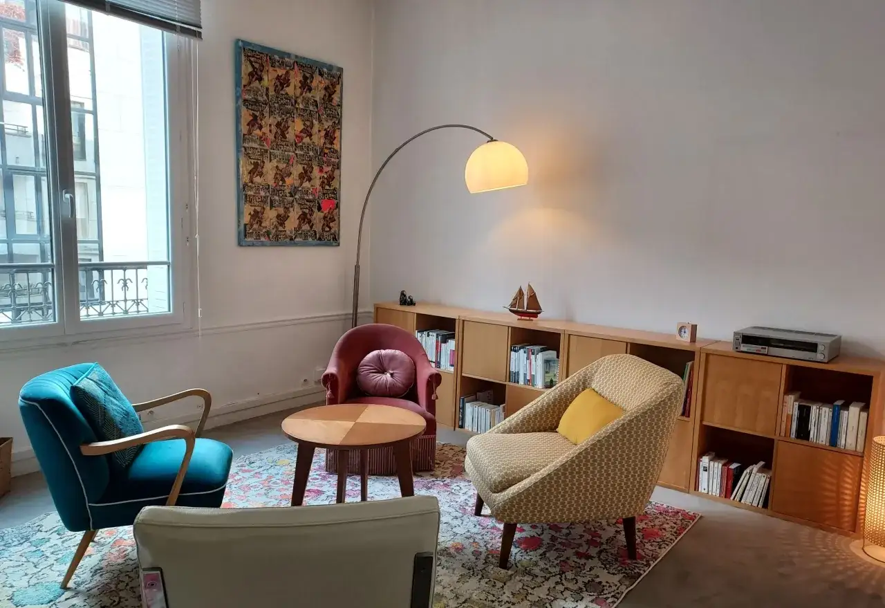 Salon cosy avec fauteuils confortables, idéal pour une thérapie de couples. Une lampe arche éclaire doucement la pièce.