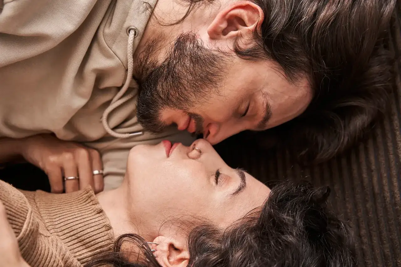 Un couple s'embrasse tendrement, leurs visages proches, un soupir amoureux flottant dans l'air.