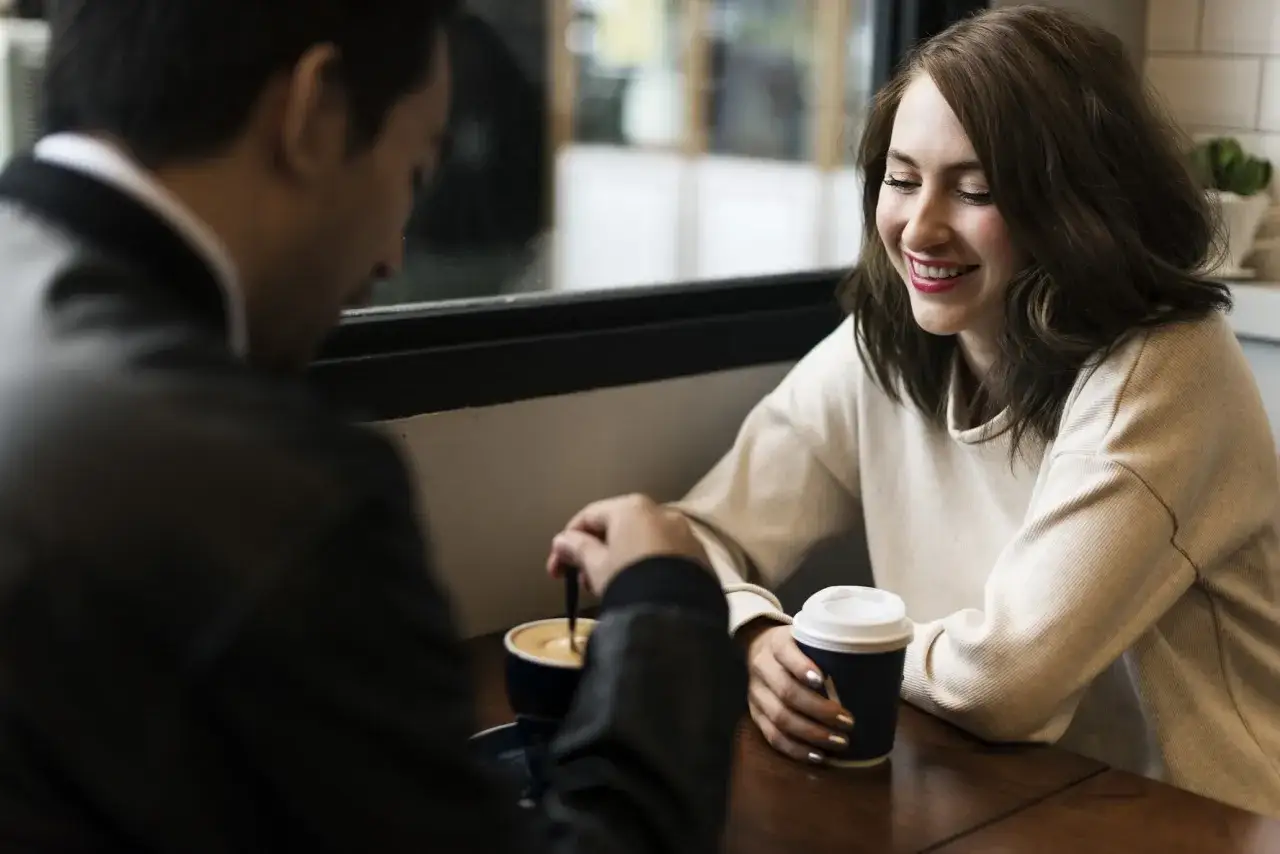 Un couple partage un café, elle sourit, lui remue sa boisson. Qui doit envoyer le premier message après ce date ?