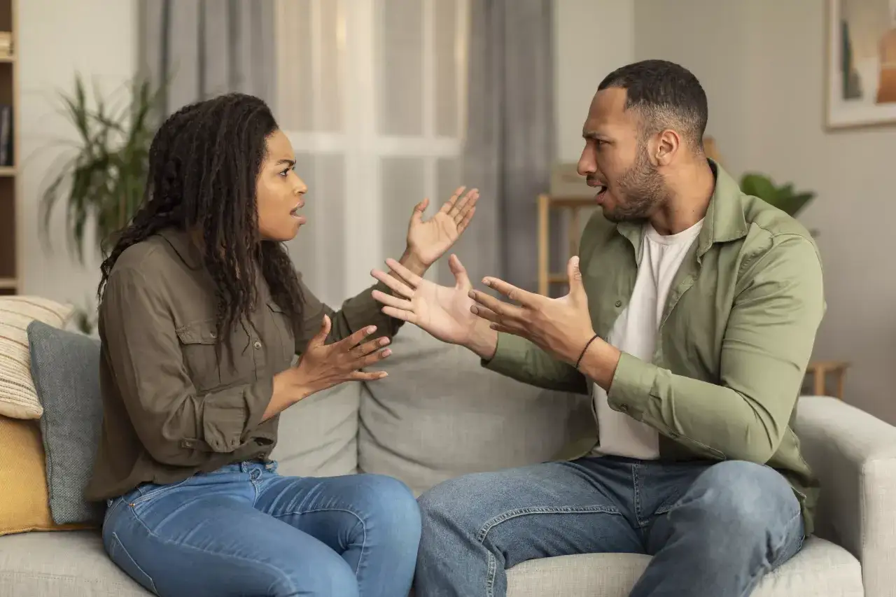 Un couple discute vivement sur un canapé. Elle semble frustrée, lui tente de l'expliquer, mais comment faire parler quelqu'un qui ne veut pas parler ?
