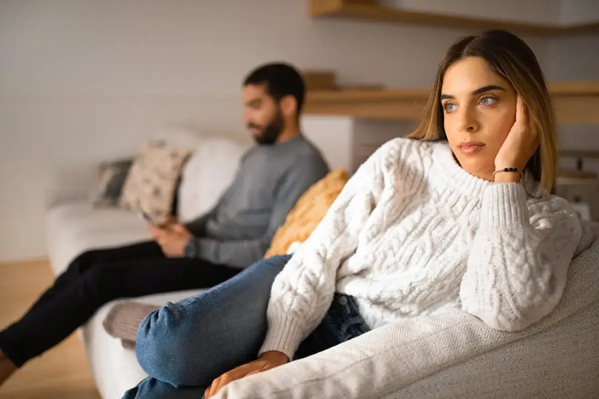 Un couple s'ennuie dans son couple, chacun absorb&eacute; par son t&eacute;l&eacute;phone sur le canap&eacute;, le regard perdu dans le vide.