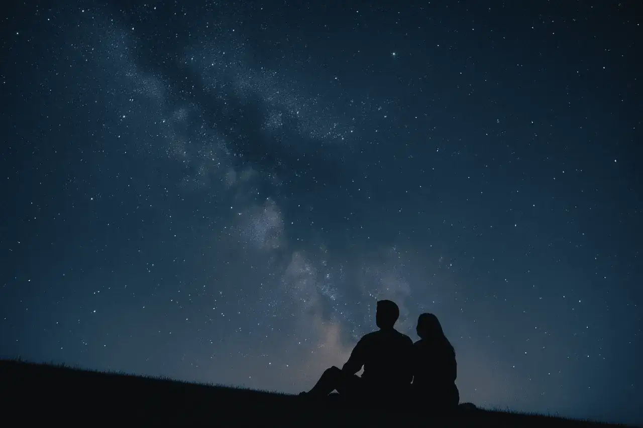 Un couple en silhouette admire la Voie lact&eacute;e, une parfaite id&eacute;e de rendez-vous romantique sous les &eacute;toiles.