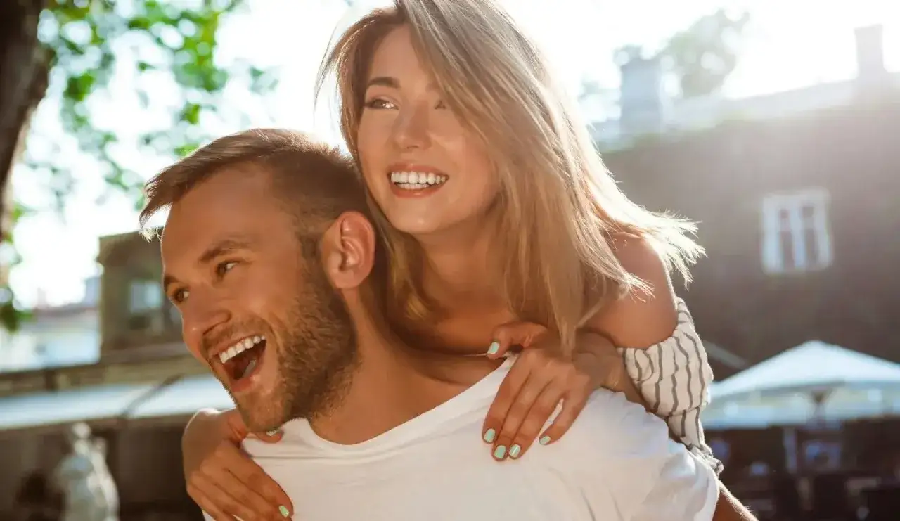 Un couple heureux, elle sur son dos, riant. Une sc&egrave;ne parfaite pour comment attiser le d&eacute;sir d'un homme.