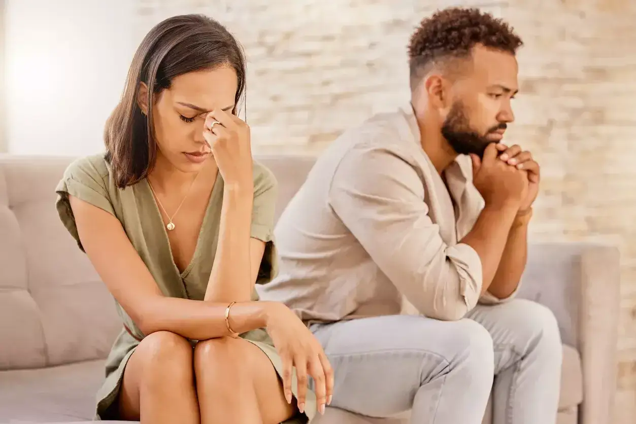 Un couple assis dos &agrave; dos sur un canap&eacute;, visiblement en conflit. Elle se tient la t&ecirc;te, l'air d&eacute;sesp&eacute;r&eacute;e, comme si je ne supporte plus ma femme.