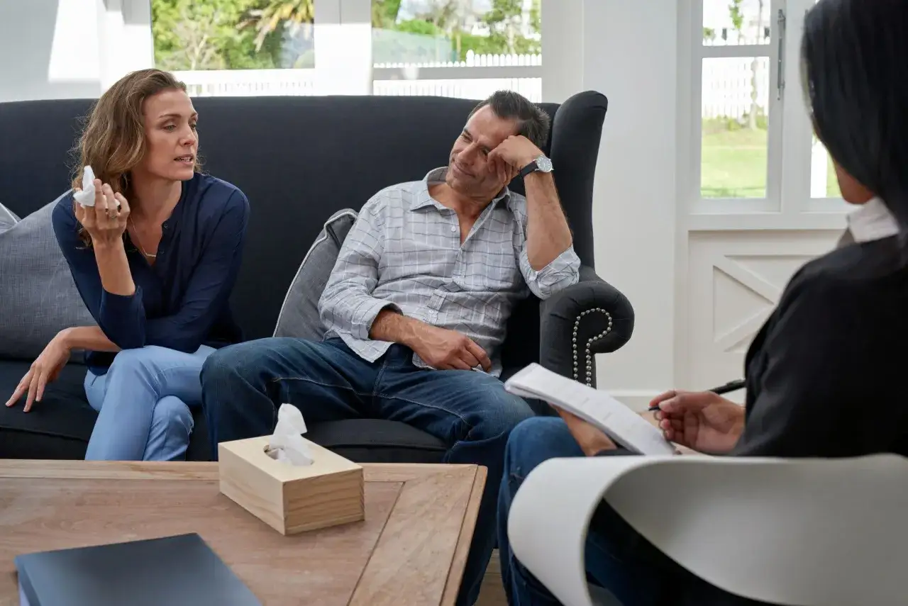 Un couple discute avec un th&eacute;rapeute, la femme tient un mouchoir, le d&eacute;but d'une th&eacute;rapie de couple.