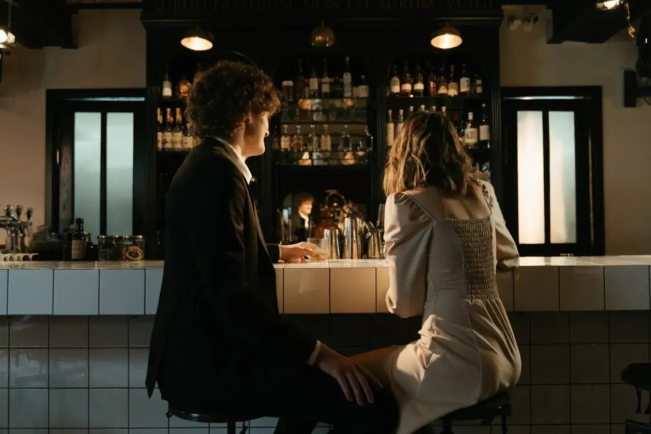 Couple au bar, se demandant combien de temps attendre après un premier rendez-vous.