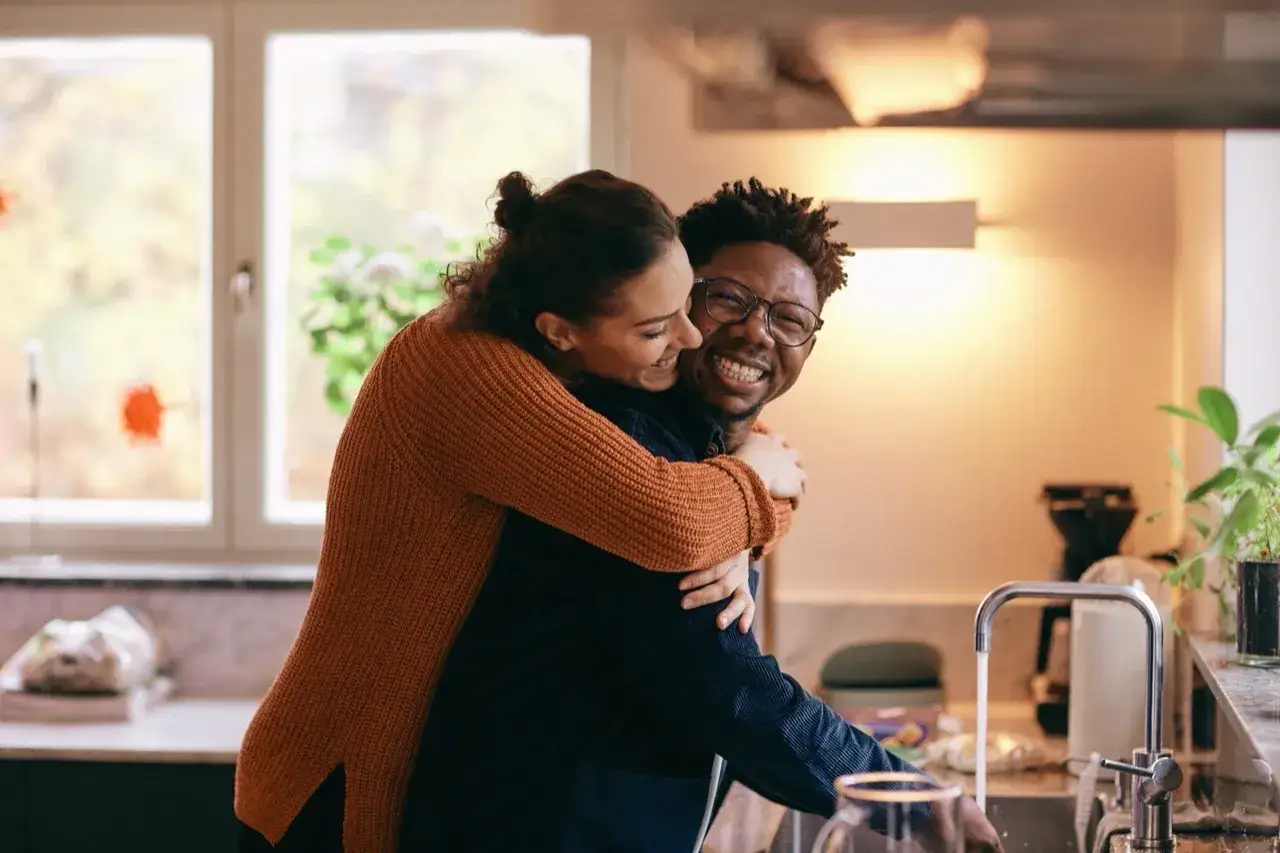 Un couple complice et heureux dans la cuisine. Elle le serre dans ses bras, un sourire radieux aux lèvres. Une scène qui pourrait bien être la clé pour savoir comment sortir de la friendzone.