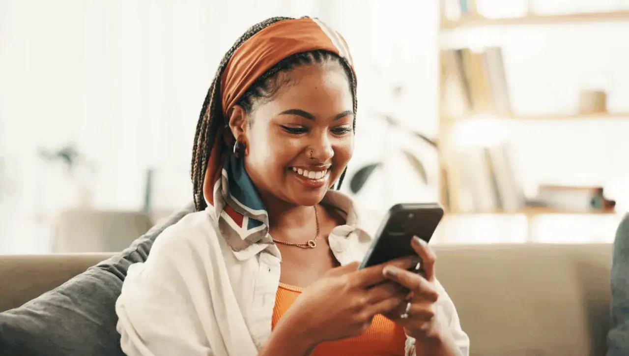 Une jeune femme souriante regarde son téléphone, peut-être en attendant qu'il ne répond pas à mon message.