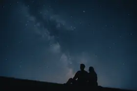 Un couple en silhouette admire la Voie lactée. Une idée de rendez-vous romantique parfait sous les étoiles.