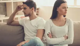 Un couple assis sur un canapé, dos à dos, visiblement en conflit. Elle croise les bras, l'air contrarié, comme s'il la prenait pour acquise.
