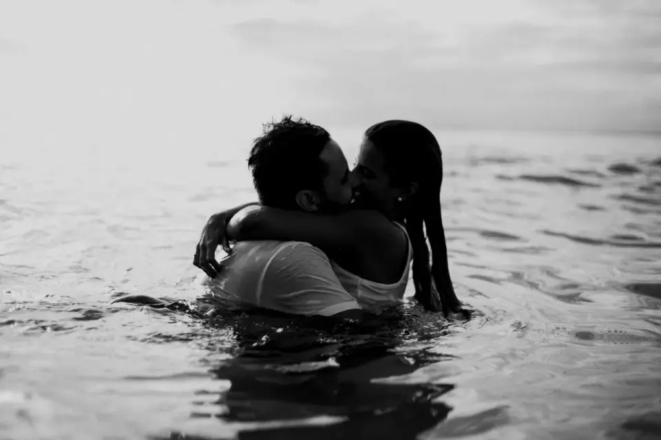 Un homme enlace une femme dans l'eau, leurs lèvres se cherchent. C'est le moment où un homme te dit qu'il a envie de toi, une promesse silencieuse.